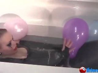 Latex kledd unge hunn med ballonger i en badekar
